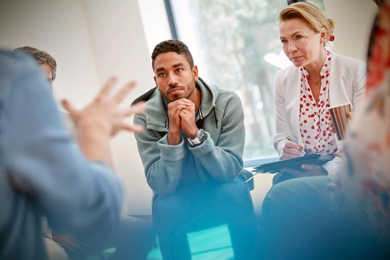 two people leaning forward, listening to a person in the foreground